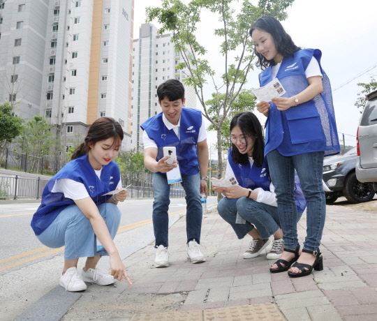 삼성디스플레이 신입사원들이 파손된 보행시설을 발견하고, 스마트폰 맵시스템을 활용해 해당 위치를 입력하고 있다. <삼성디스플레이 제공>